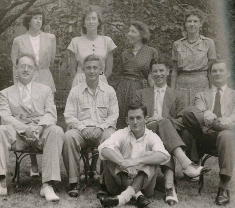 1940s photograph of men and women in old fashioned clothes smiling for camera