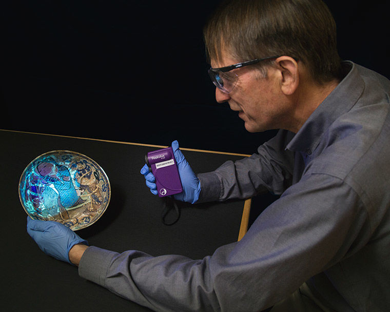 Conservator examining a ceramic dish using ultraviolet radiation