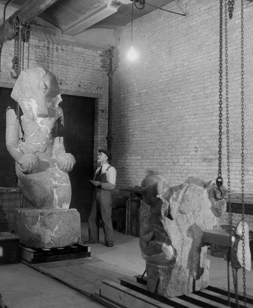 "Egyptian Tank Room Wing A Room 104 Basement Floor," October 24, 1930, showing Chris Watt with a granite figure of Hatshepsut (29.3.1) during restoration