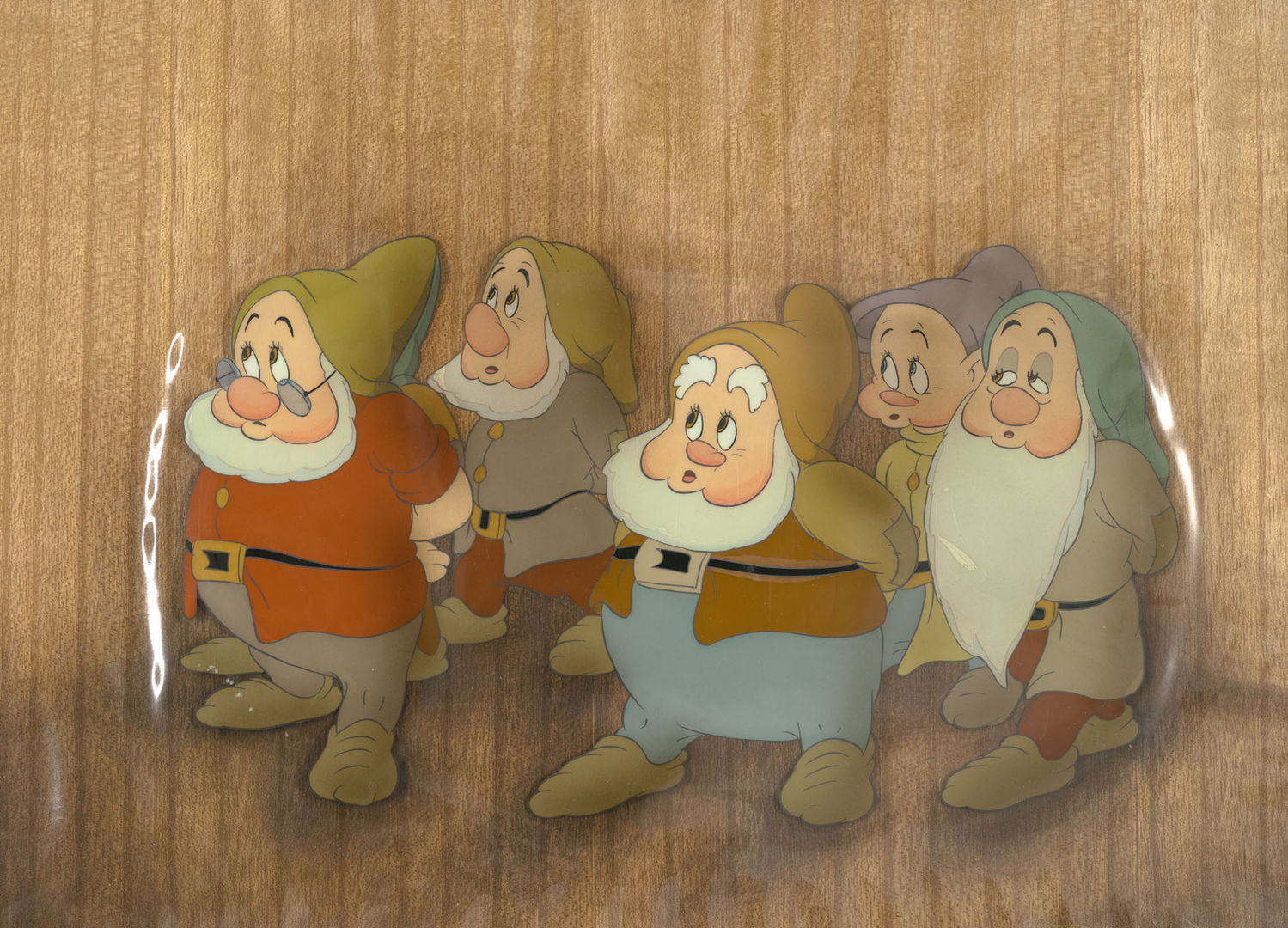 Five dwarves look up and to the left on a wooden background.