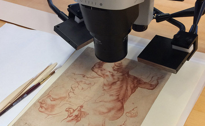 A Michelangelo drawing under a microscope with paintbrushes to its left