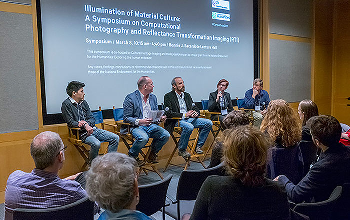 Panel of speakers sitting in front of a screen