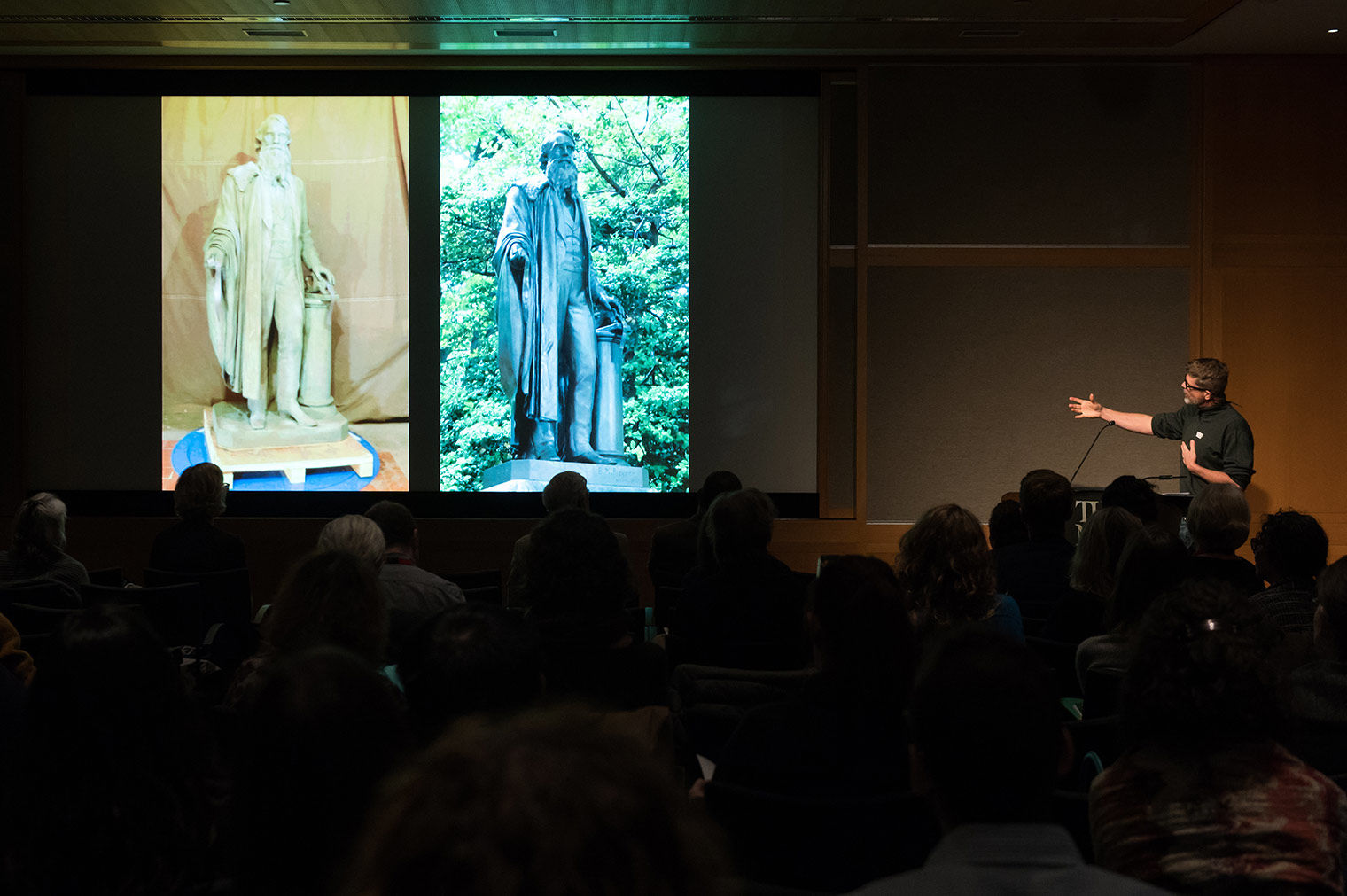 Male speaker presents a slide featuring pictures of two sculptures