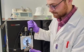 The scientist Vaclav Krupicka of the University of Bordeaux prepares a sample for injection onto a scientific instrument called the ThermoFisher Orbitrap Eclipse Tribrid Mass Spectrometer pictured in the background.