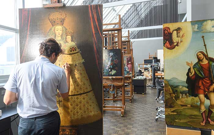 Paintings conservation fellow working on a royal portrait painting