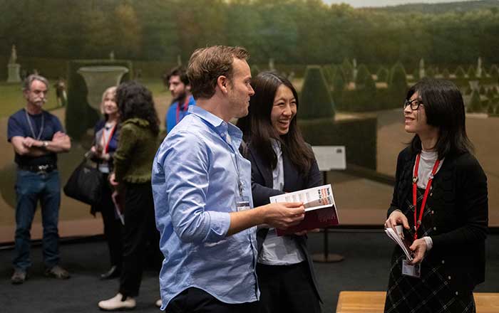 Fellows stand in a gallery discussing art with other fellows