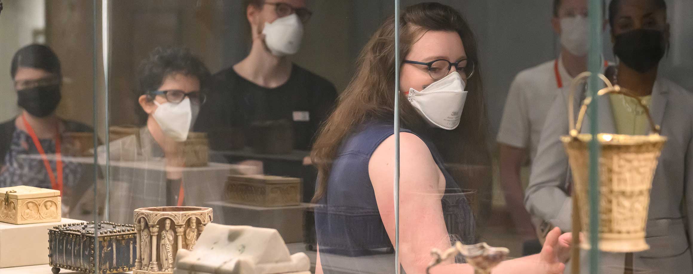 Met staff members and fellows wearing protective face masks looking at objects on display in a vitrine 