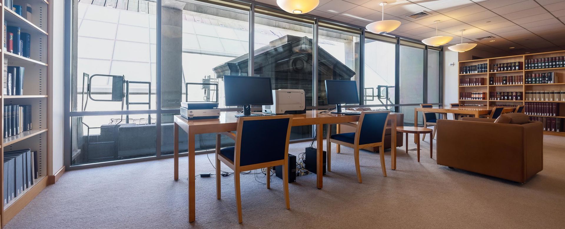 A library with shelves of books and table with computers and printers