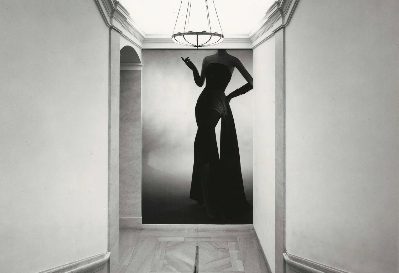 Installation photograph showing a hallway with a floor-to-ceiling photograph of a woman's body wearing a Christian Dior dress