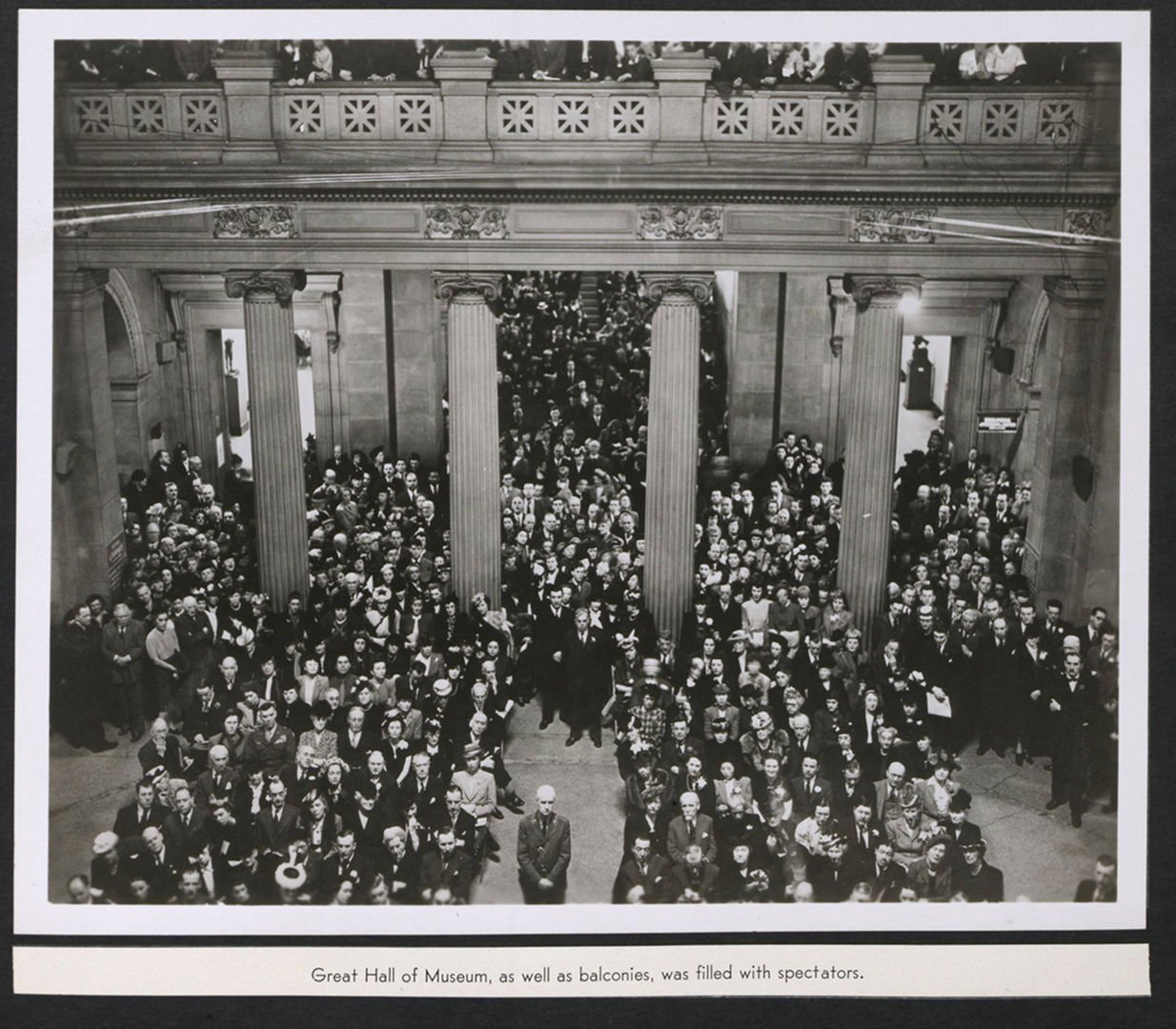 A black-and-white photograph of the Great Hall of the Metropolitan Museum of Art filled with spectators