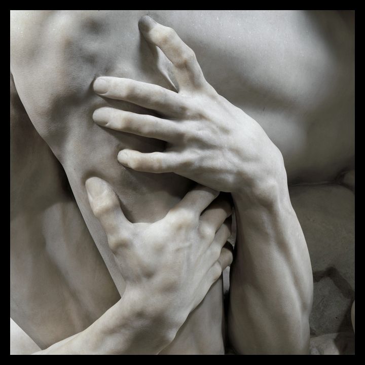 Detail view of a marble sculpture in which we see a hand grasping another piece of flesh