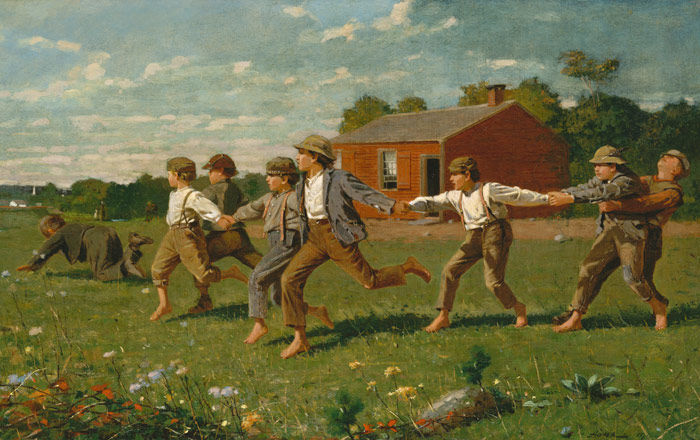 Seven boys run in a field with a red barn in the background