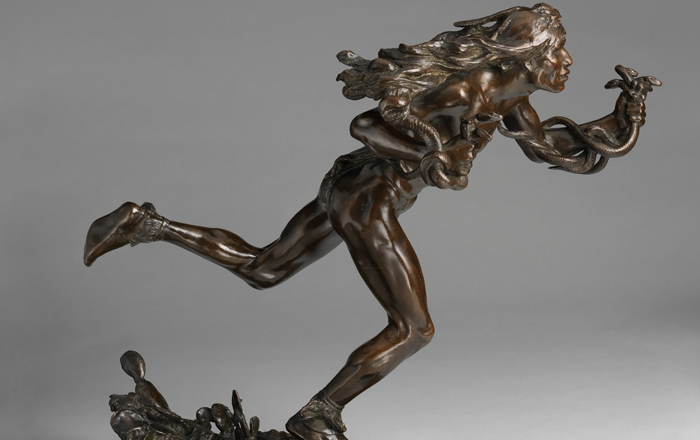A bronze statue of a woman running with snakes wrapped around her shoulders and arm