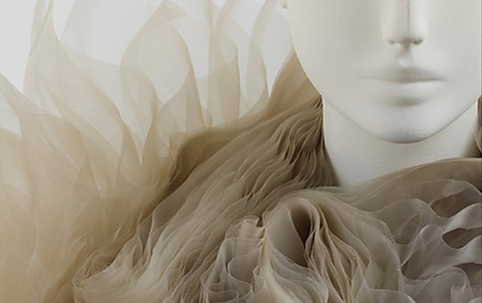 A mannequin wears a ruffled, bone-colored garment