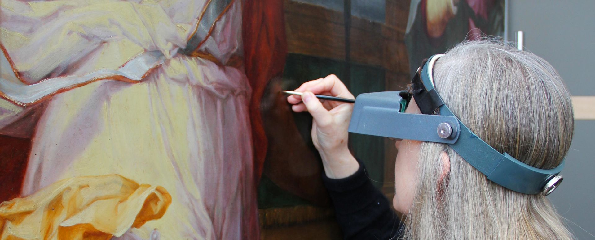 A conservator analyzes a painting up close