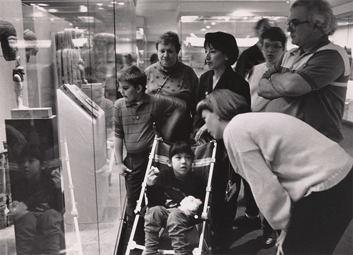 Archival photo of adults and children looking at Egyptian art. 