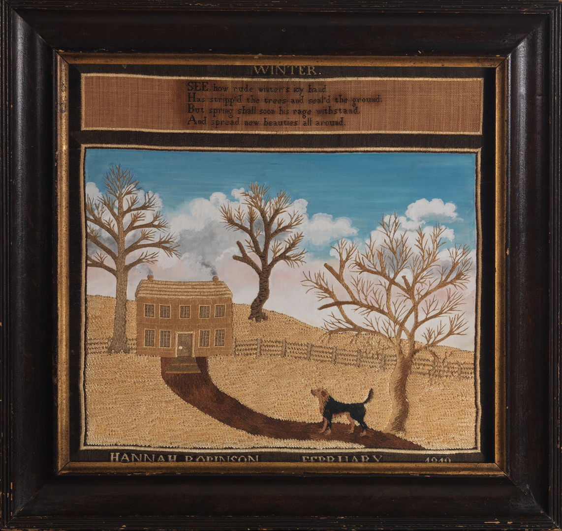 Image of a needlework picture by Lucy Huntington showing a winter landscape embroidered on cloth with a black wooden frame. In the scene a dog follows a brown dirt road towards a small cabin with on the top of a hill covered in dried yellow grass. Three trees stand stall against a blue sky with white clouds.