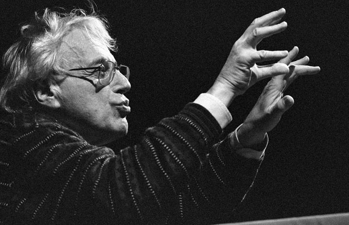 Black-and-white photo of Györgi Ligeti with his hands in the air as to conduct