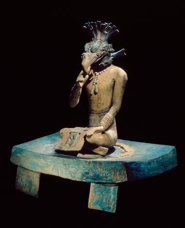 Photo of a Maya figure wearing a bird mask, shown against a black background