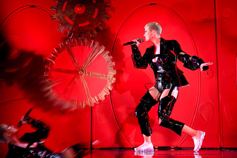Katy Perry performs against a bright red backdrop at the 2017 Met Gala celebrating Rei Kawakubo