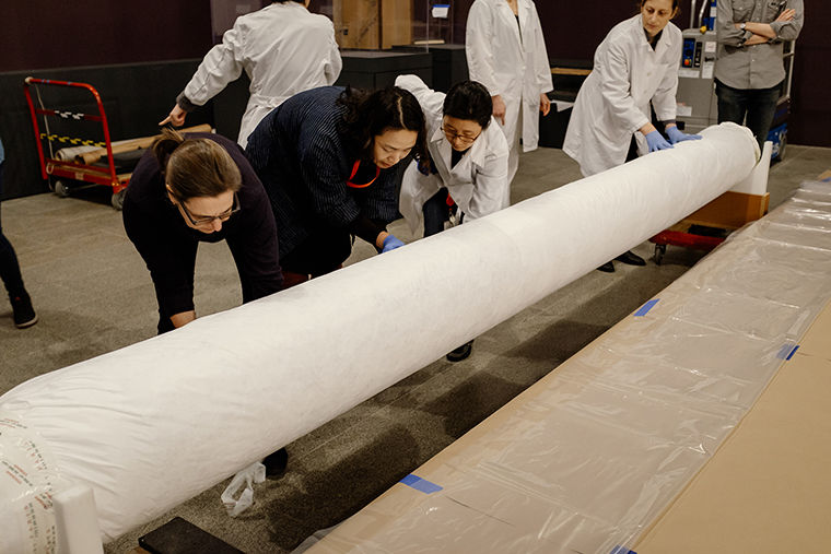 Staff from The Met unroll a work of art for installation in the exhibition Visitors to Versailles