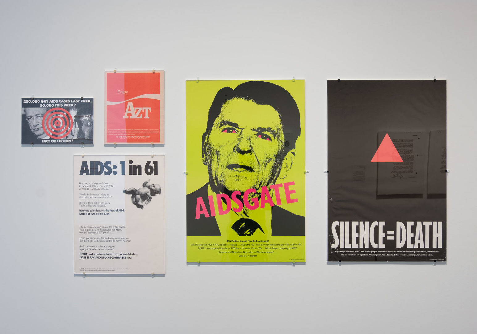 View of an gallery wall at The Met Breuer displaying five protest posters by Gran Fury and the Silence = Death Project created during the early days of the AIDS epidemic