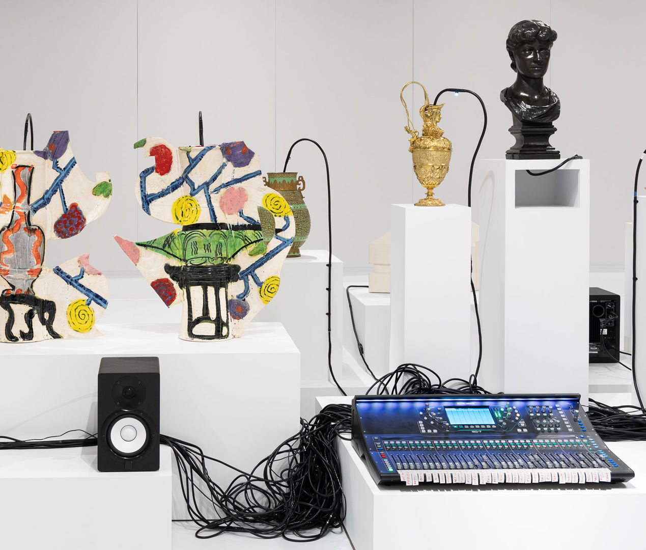 Gallery view of Oliver Beer Vessel Orchestra exhibition featuring different vessels from the museum, an audio system, and speakers.
