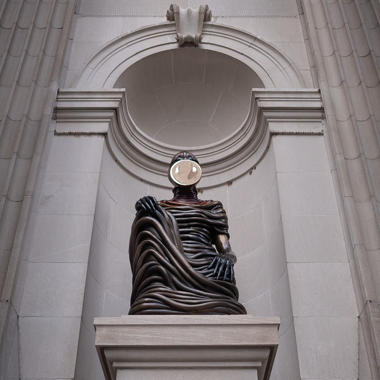 A bronze figure sits in the Metropolitan facade
