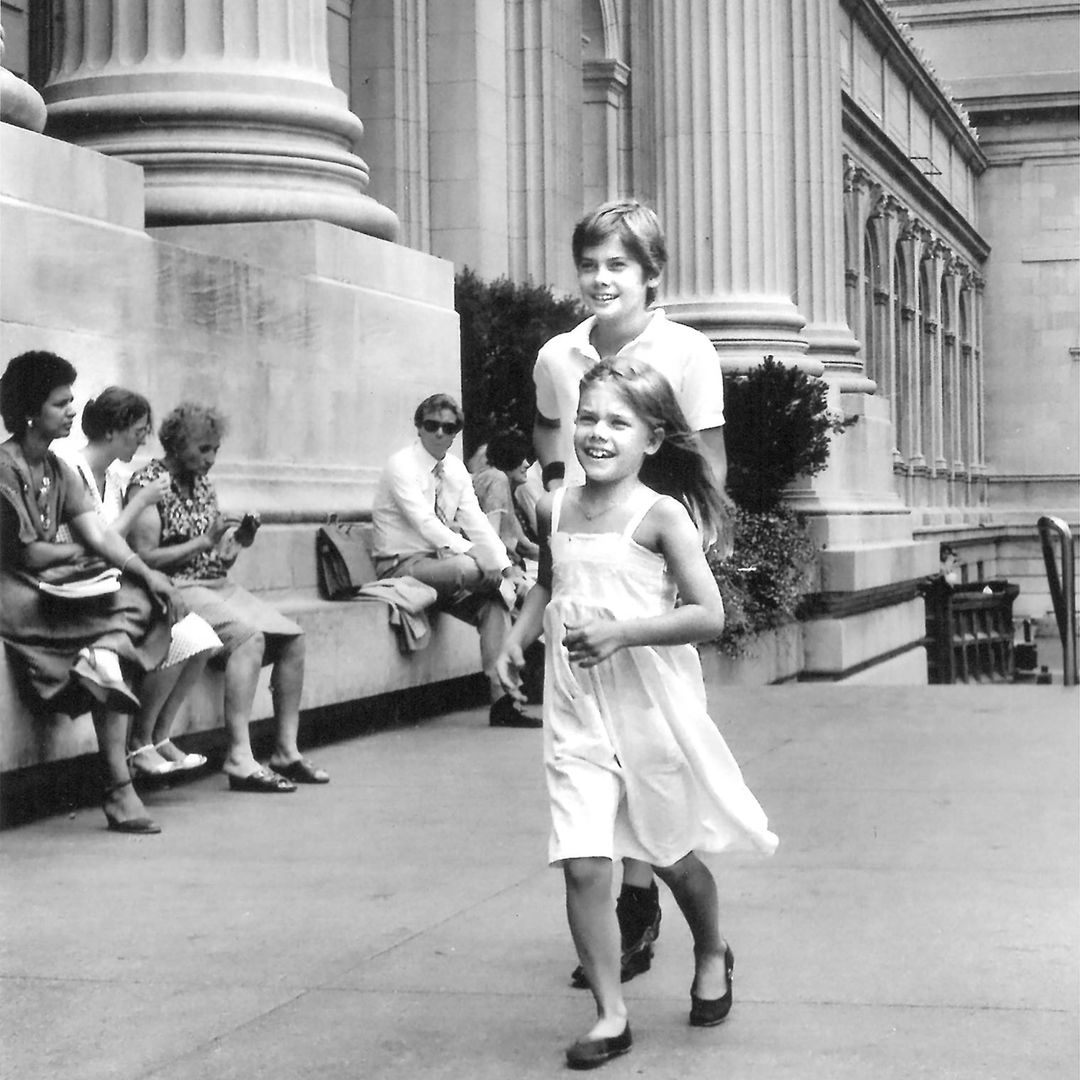 Young boy and girl running on the steps of The Met.