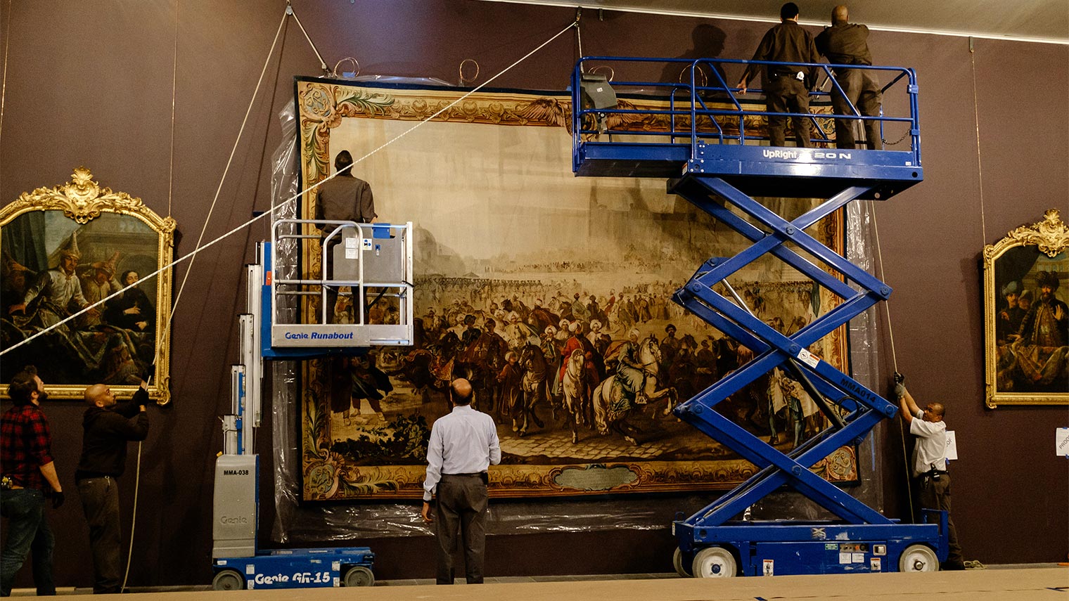 A photo of riggers installing a large tapestry