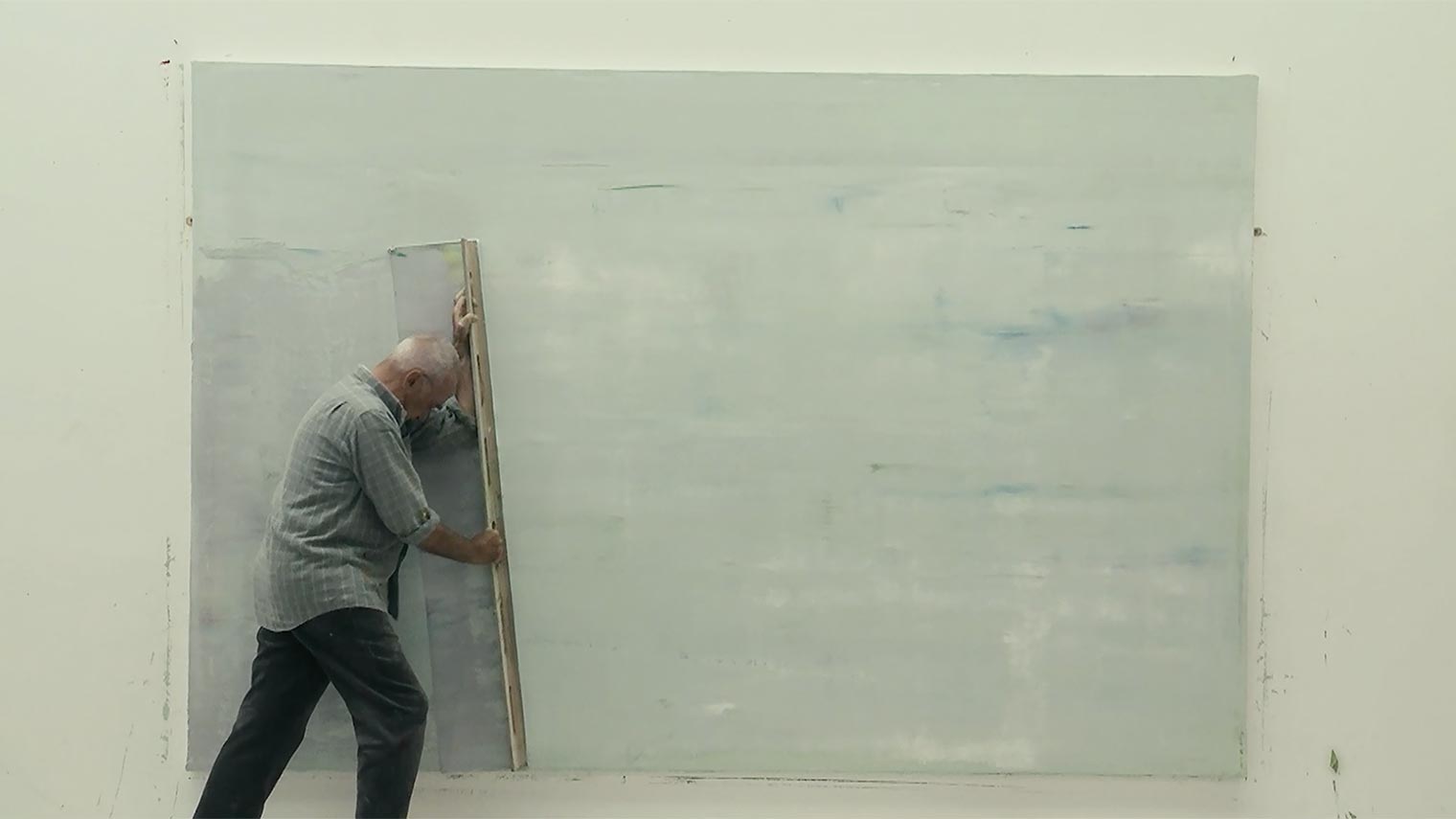 The artist Gerhard Richter draws a large squeegee across a white canvas