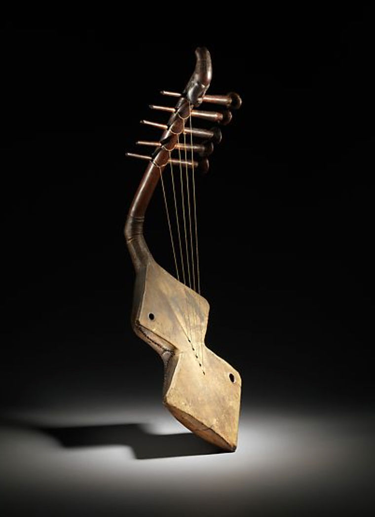 A sharp-angled wooden harp rests before a black background.
