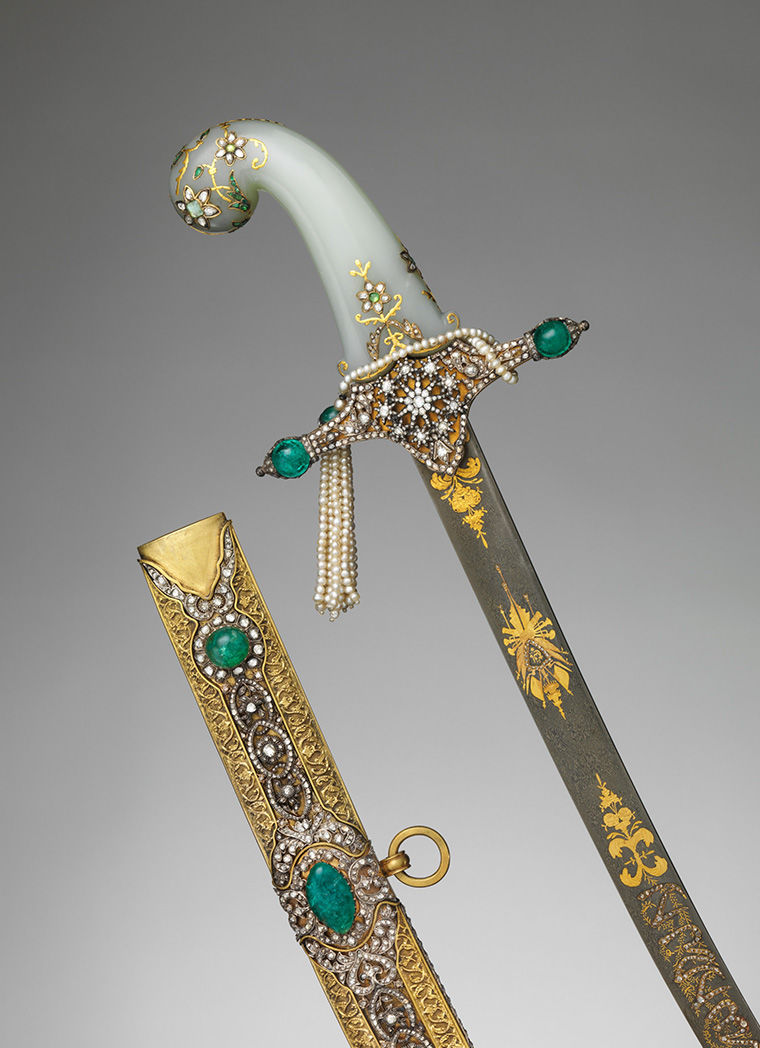 Handles of two gold, metal, and green-jeweled swords