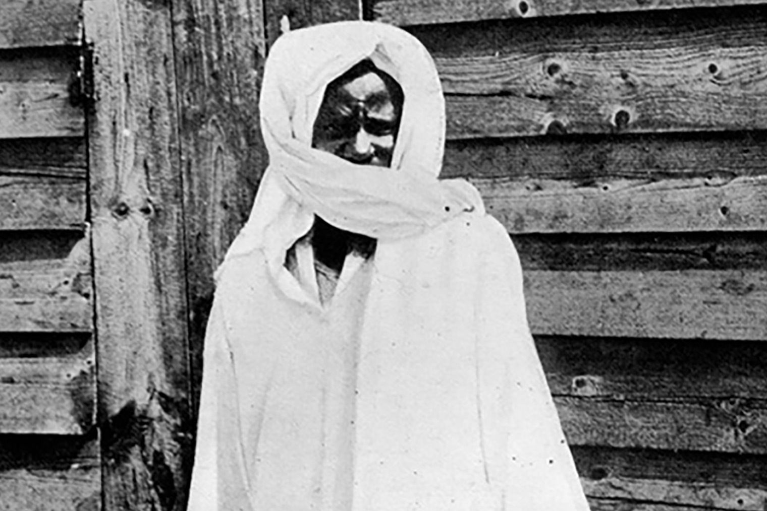 A black-and-white photo of a man shrouded in all-white cloth