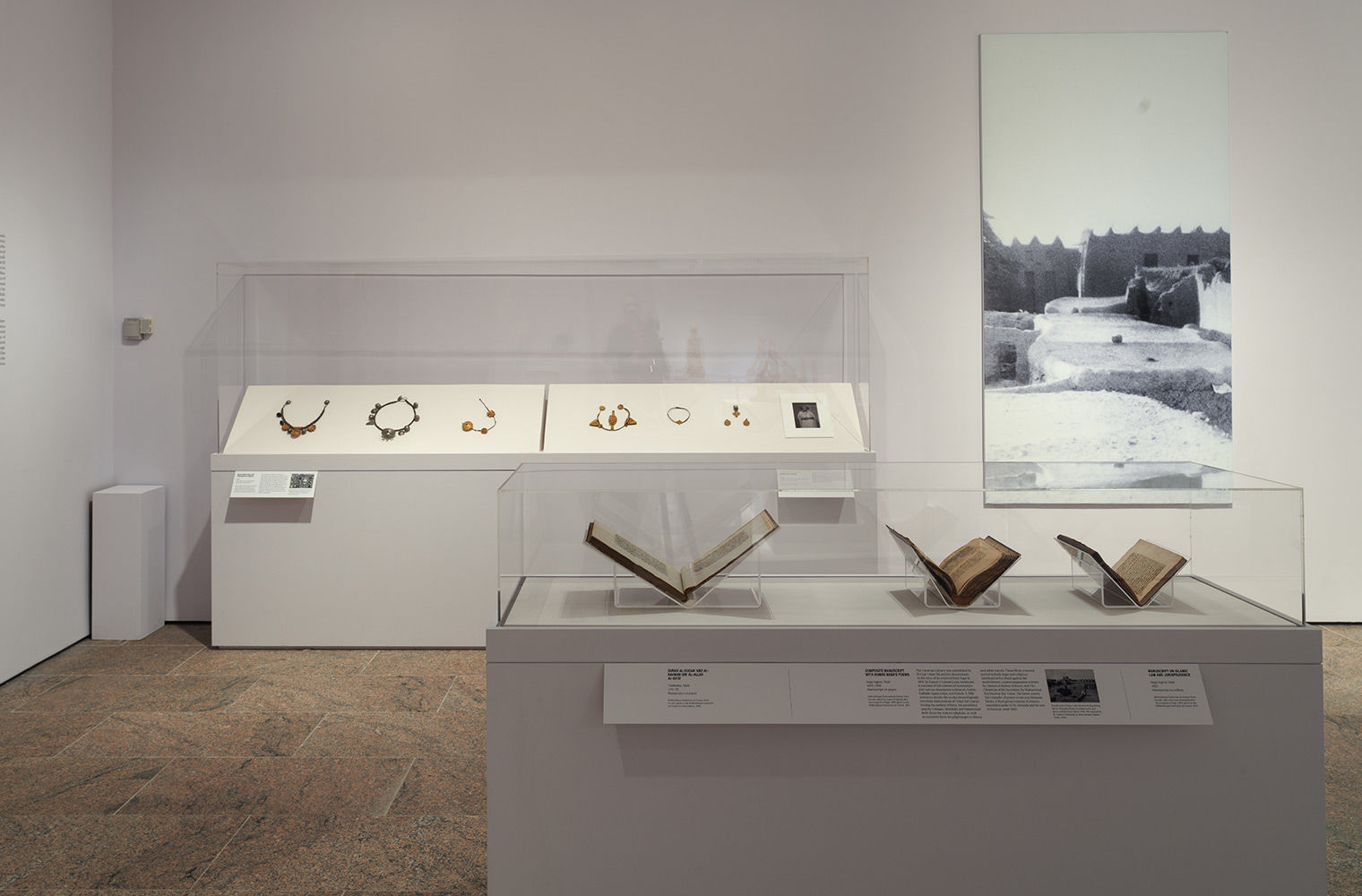 Installation view with black and white photographs and open manuscripts.