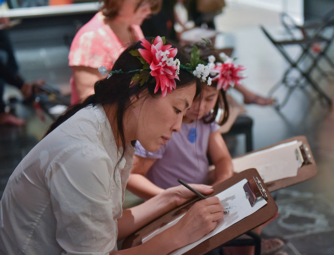Mother and her daughter wearing flower crowns drawing in the galleries