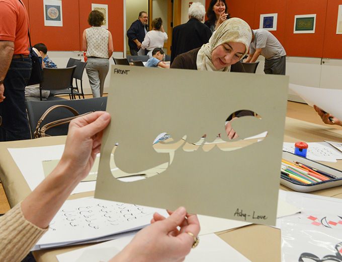 Woman holding cut-out art of Arabic calligraphy