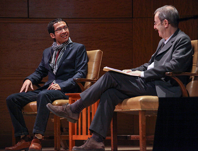 Two men sitting in chairs smiling and talking