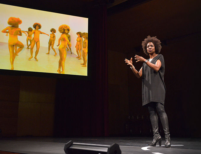 Woman with a headset microphone in front of a screen, lecturing