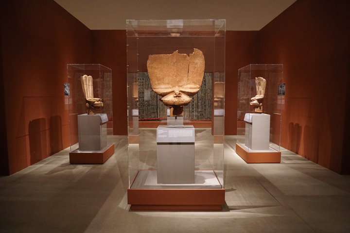 Installation view showing four of the wooden tsesah masks featured in the exhibition 'The Face of Dynasty'