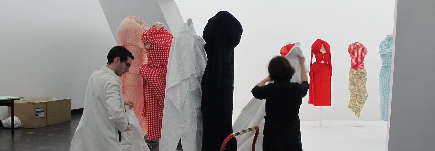 Photo of two Costume Institute staff members installing works in the Rei Kawakubo exhibition