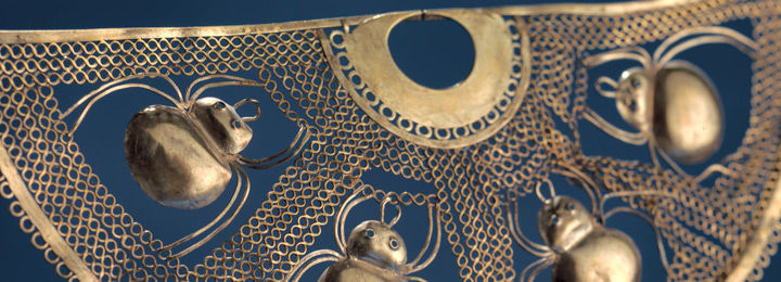 Detail view of an ancient Peruvian nose ornament adorned with spider figures