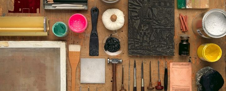 Birds-eye view of various printmaking tools laid out on a table.