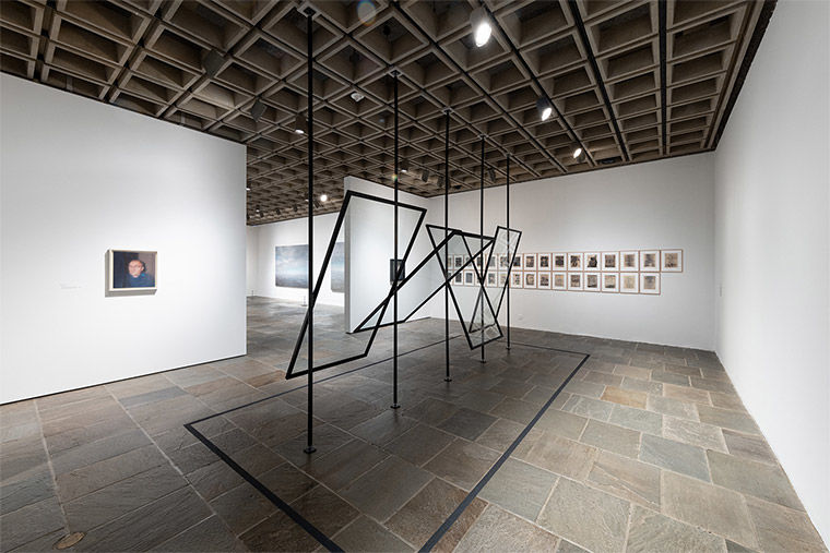 Installation view of Gerhard Richter: Painting After All at The Met Breuer featuring a large abstract sculpture made from four panes of glass at various angles supported by fark metal
