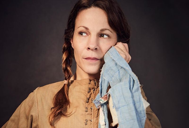 Actress Lili Taylor with her hair in two braids, holding a piece of fabric to her face as if wiping away a tear