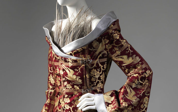 Detail view of an elegant red-and-gold ensemble by Alexander McQueen