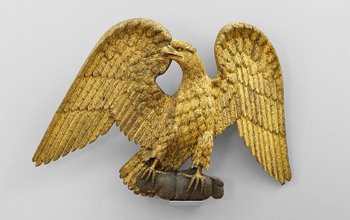 Figure of an eagle, gold sculpture with wings open, looking to the left