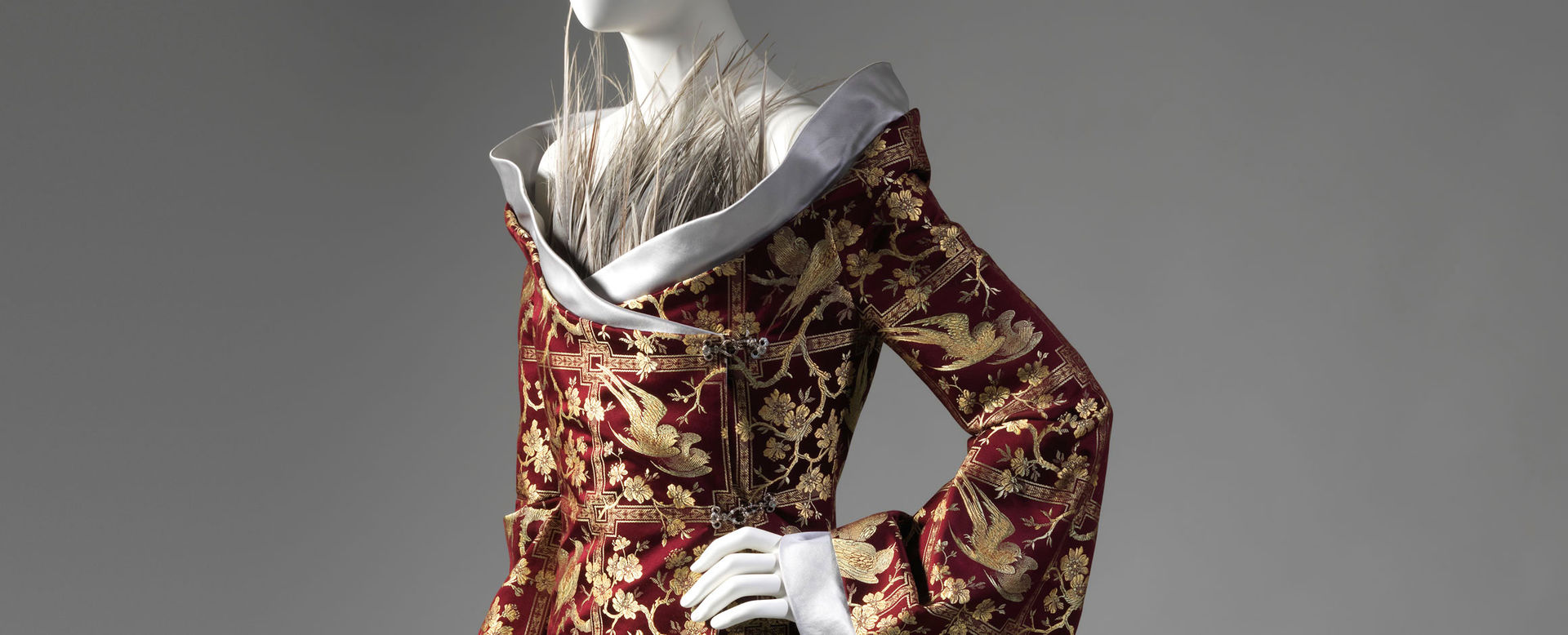 Detail view of an elegant red-and-gold ensemble by Alexander McQueen