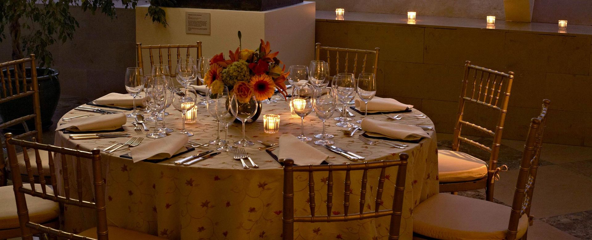 Circular table with flowers in the middle and low lit candles during the evening