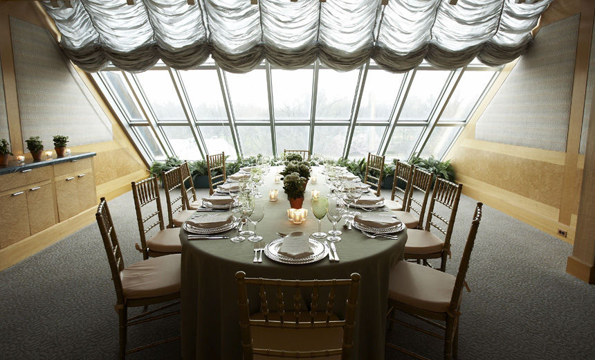 An intimate and elegant room with skylights at the far end; a dining room table and chairs are set with an elegant formal service